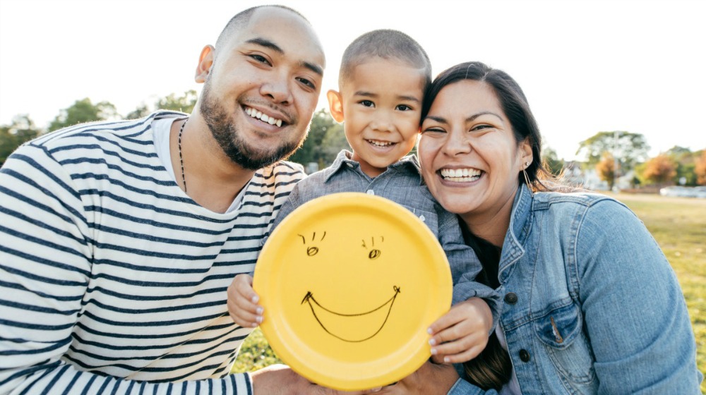Parents and child holding plate with smiley face